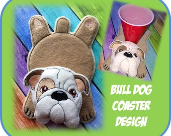 May include: A fabric bulldog coaster in shades of brown, white, and tan. The coaster features a bulldog face and body, with a matching base. A red cup rests on a similar coaster in the image. Text reads "BULL DOG COASTER DESIGN."
