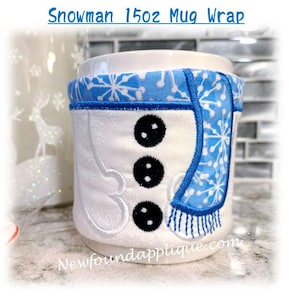 May include: A white mug with a snowman design. The snowman is wearing a blue scarf with white snowflakes. The mug is 15 oz and has the text "Newfoundapplique.com" on the bottom.