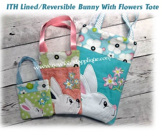 May include: Three reversible tote bags with bunny and flower embroidery. The smallest bag is green and white with polka dots. The middle bag is pink and white with floral print. The largest bag is blue and white with floral print. All bags have white bunny embroidery with pink ears and flowers.