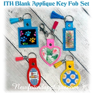 May include: A set of five key fobs in various shapes and colors. Designs include paw prints, a peacock feather, a heart with a floral pattern, a school supplies design, and a daisy pattern. Each fob has a tassel and a metal keyring.