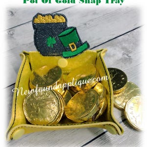 May include: A yellow felt snap tray with a green leprechaun hat and pot of gold applique. The tray is filled with gold chocolate coins.