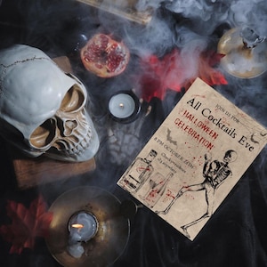 Pode incluir: Natureza morta de Halloween com uma caveira, velas e um convite. O convite diz "All Cocktails Eve Halloween Celebration". A cena inclui uma romã e folhas vermelhas, com uma atmosfera esfumaçada.
