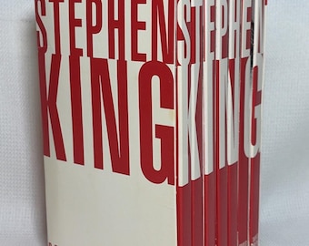 Könnte beinhalten: Ein Box-Set von Insomnia von Stephen King, gelesen von Eli Wallach, mit 21 Audiokassetten. Die weiß-rote Verpackung zeigt eine große, rote Schrift. Die Rücken der einzelnen Kassettenhüllen sind sichtbar und in fortlaufender Reihenfolge nummeriert.