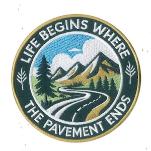 May include: Embroidered patch with a circular design featuring a mountain landscape and a winding road. The text "LIFE BEGINS WHERE THE PAVEMENT ENDS" is in a circular border around the image. The patch has a green, gold, blue, and white color scheme.