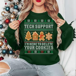 May include: A dark green Christmas jumper with the text "TECH SUPPORT" and "I'M HERE TO DELETE YOUR COOKIES" in white. The jumper features a pattern of snowflakes, Christmas trees, a gingerbread house, a gingerbread man, and a snowflake.