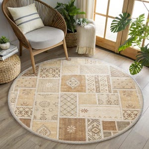 May include: A round area rug featuring a patchwork design with various rectangular and square sections in shades of beige, tan, and brown. The pattern includes diverse geometric shapes, floral motifs, and cross-hatch textures across the surface.