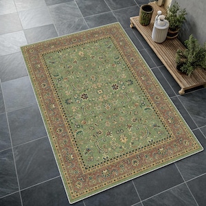 May include: A rectangular, green area rug with an intricate floral pattern and a reddish-brown border. The rug's design features a central field of green with various floral motifs in shades of yellow, red, and blue. The border is a contrasting reddish-brown with a detailed pattern.