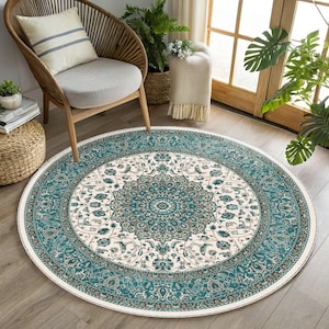May include: A round area rug featuring a central floral medallion pattern in shades of teal, cream, and dark brown. The design includes intricate botanical motifs and a wide, detailed border with repeating patterns, creating a symmetrical layout.