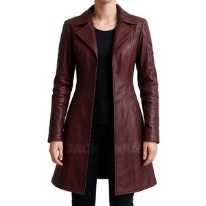 May include: A burgundy leather coat with a tailored fit. The coat features a notched collar, long sleeves, and a flared hem. The coat has a button closure and is designed with seams for a structured look. The coat is a deep red colour.