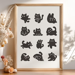 May include: A framed cross-stitch featuring twelve black cat silhouettes in various poses. The cats are stitched on a white background, and the frame is made of light-colored wood. The artwork is displayed on a wooden surface.