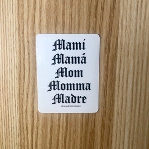 May include: White sticker with black text in a gothic font. The text reads "Mami Mamá Mom Momma Madre" and "@academicmami".