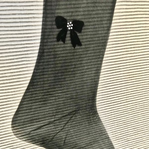 May include: Black sheer stockings with a black velvet bow and a white rhinestone embellishment.