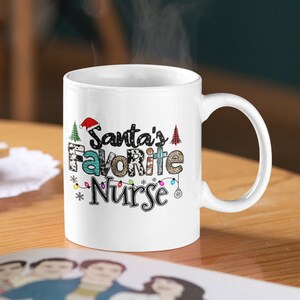 May include: White ceramic mug with a Christmas-themed design. The mug features the text "Santa's Favorite Nurse" with a red Santa hat, Christmas trees, and lights.
