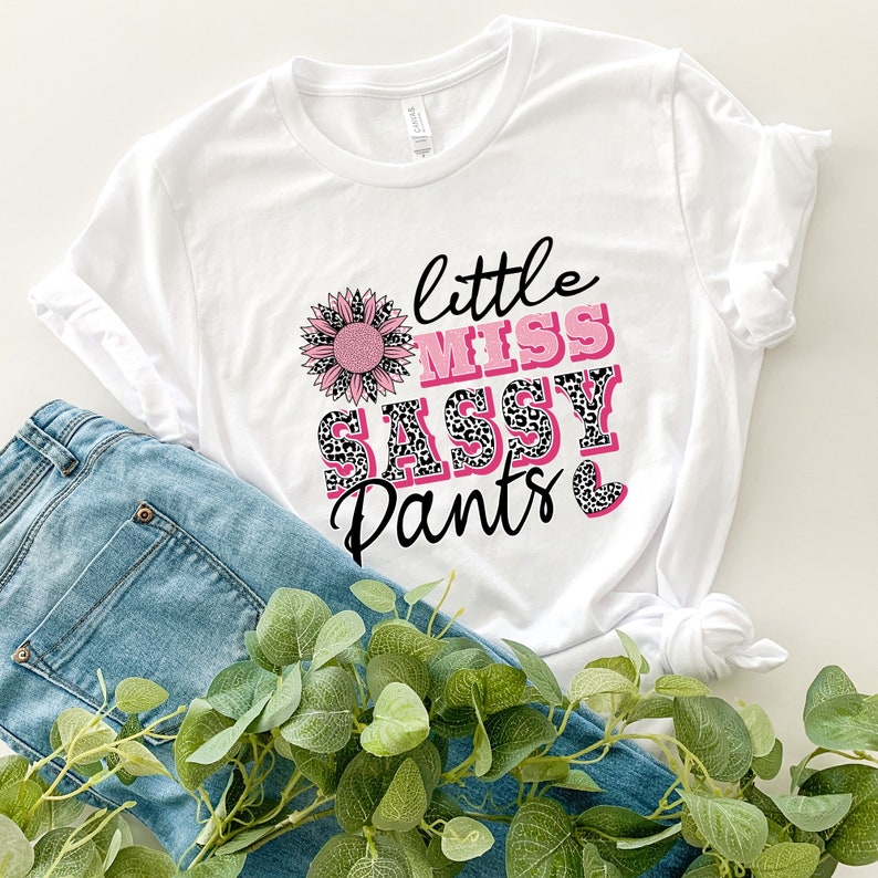 May include: White t-shirt with a pink sunflower, the text "little miss sassy pants" and a pink heart.
