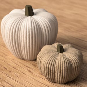May include: Two decorative pumpkins on a wooden surface. The larger one is off-white, the smaller one tan. Both have ribbed textures and dark green stems. Ideal for autumn decor, these pumpkins add a seasonal touch.