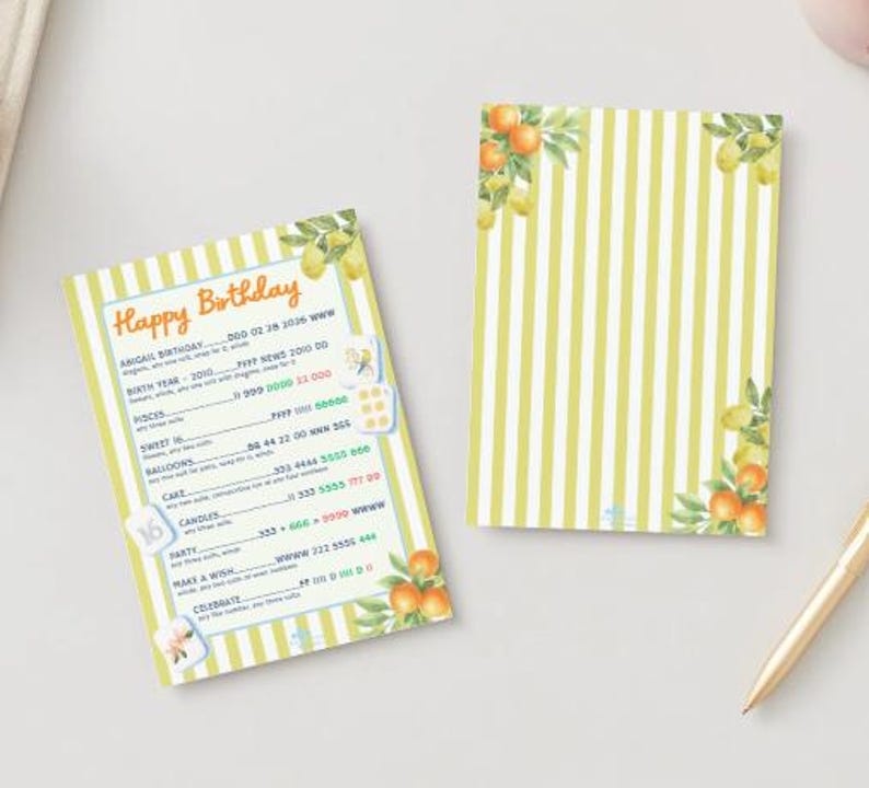 May include: Two birthday-themed cards with a yellow and white striped pattern. One card has the text "Happy Birthday" and other details. Both cards feature watercolor illustrations of oranges and lemons. A gold pen rests nearby.