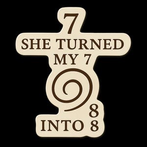 May include: A cream-colored wooden plaque with the text "7 SHE TURNED MY 7 INTO 8" in dark brown. The design includes a spiral and the numbers 7 and 8. The plaque has a unique shape and is set against a black background.