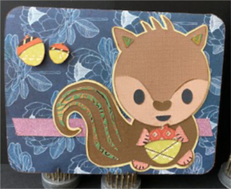 May include: A brown squirrel with a bushy tail holding a basket of yellow and red acorns. The squirrel is on a blue background with a floral pattern.