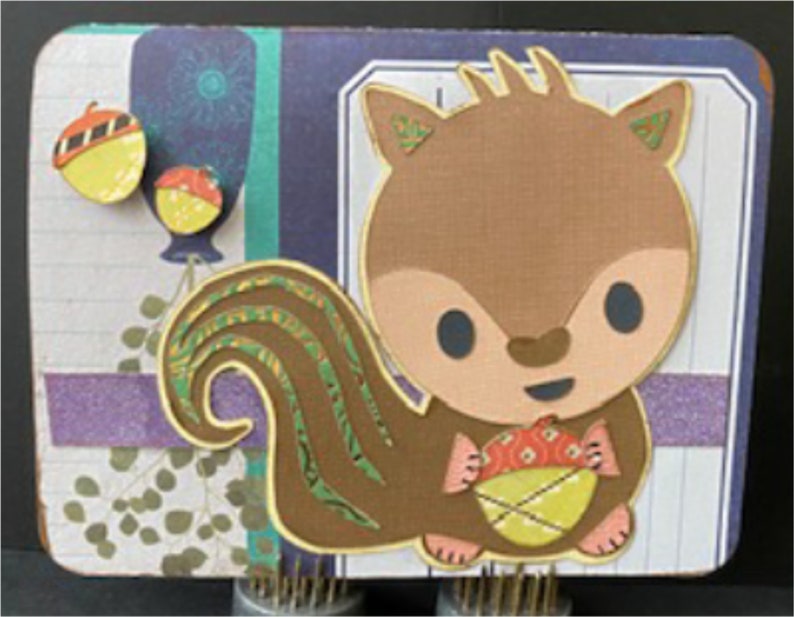 May include: A brown squirrel with a bushy tail, holding a yellow acorn. The squirrel has a cute, cartoon-like face with big eyes and a small nose. The background is a colourful patterned paper with a purple stripe.