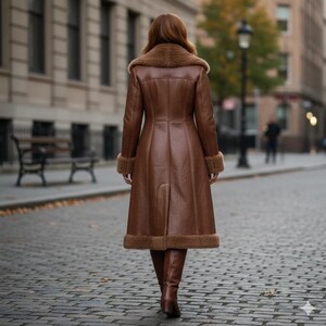 Peut inclure: Un long manteau en cuir marron avec un col, des poignets et un ourlet en fausse fourrure. Le manteau arrive au genou et a une coupe ajust&eacute;e. La personne s'&eacute;loigne sur une rue pav&eacute;e.