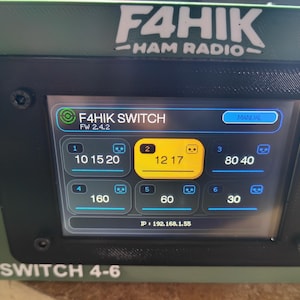 May include: A green and black electronic device with the text "F4HIK HAM RADIO" at the top. The screen displays "F4HIK SWITCH" and various numerical values within blue and yellow boxes. The device is labeled "SWITCH 4-6".