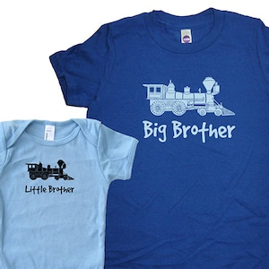 May include: A blue t-shirt with a white train and the text "Big Brother" and a light blue baby onesie with a black train and the text "Little Brother".