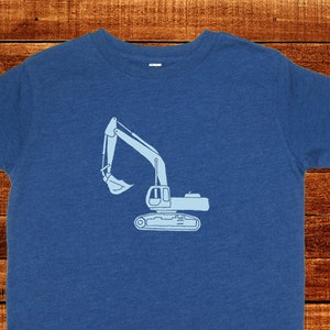 May include: A blue t-shirt with a light blue outline of an excavator on the front.