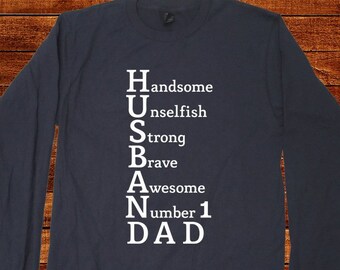 May include: Navy blue long-sleeve shirt with white text that reads "Husband" with the letters representing the words "Handsome, Unselfish, Strong, Brave, Awesome, Number 1, Dad".