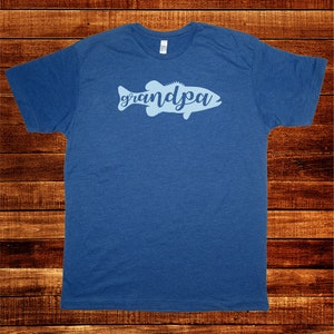 May include: A blue t-shirt with a light blue silhouette of a fish with the word "grandpa" written inside the fish.