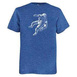 May include: Blue crew neck t-shirt featuring a white graphic of an astronaut in a spacesuit. The astronaut is depicted floating. The t-shirt is made of a soft, comfortable material.