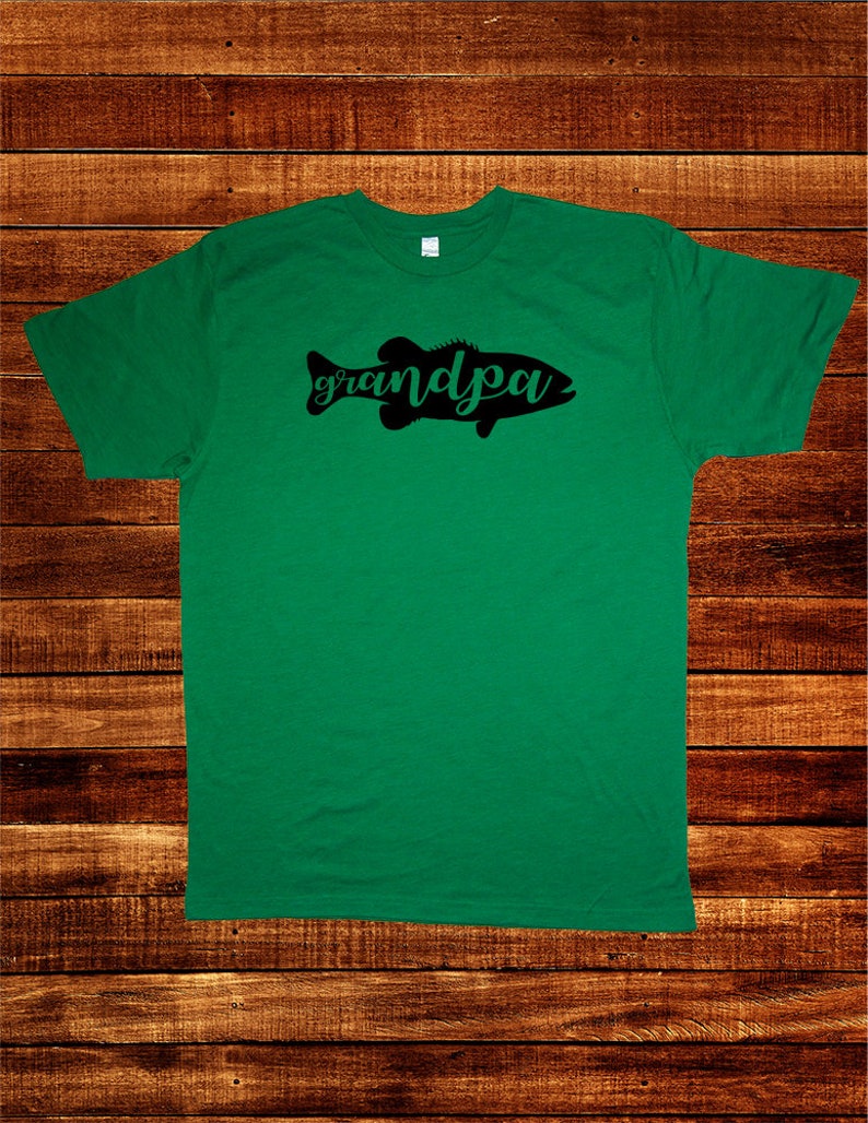 May include: Green t-shirt with a black silhouette of a fish and the word "grandpa" written in cursive.