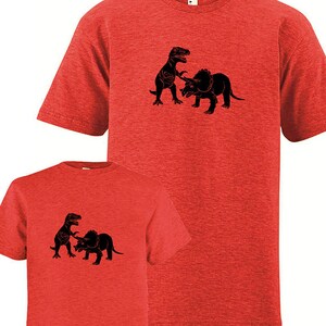 Puede incluir: Dos camisetas rojas con una silueta negra de un dinosaurio atacando a un triceratops. Las camisetas son un conjunto a juego para adultos y ni&ntilde;os.