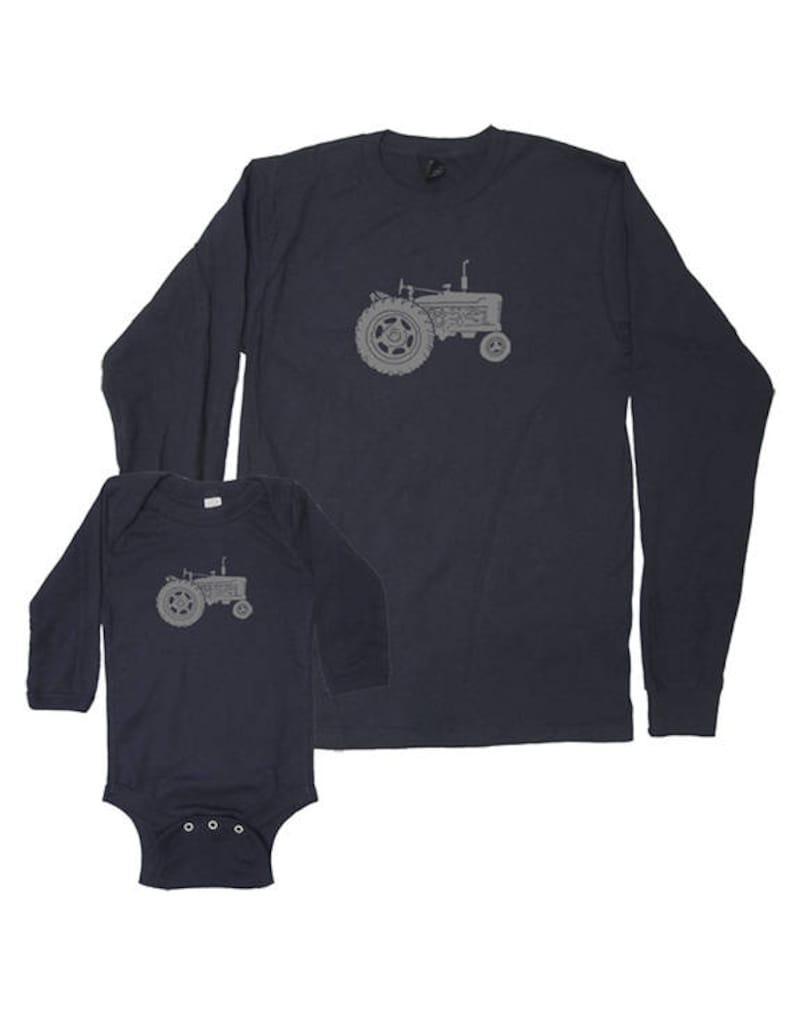 Pu&ograve; includere: Una maglietta a maniche lunghe blu navy e un body per neonato blu navy con un grafico di trattore grigio.