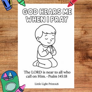 Puede incluir: Una página para colorear en blanco y negro con el texto "GOD HEARS ME WHEN I PRAY" y un dibujo de un niño arrodillado en oración. También se incluye el texto "The LORD is near to all who call on Him. - Salmo 145:18". Los crayones están esparcidos por la página.