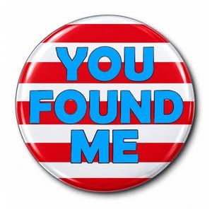 May include: A circular pinback button featuring horizontal red and white stripes. The text "YOU FOUND ME" is printed in bold, bright blue capital letters across the center of the button, covering the striped background pattern.