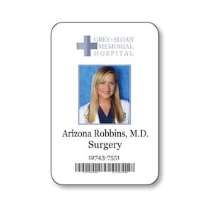 May include: A rectangular identification badge for Grey+Sloan Memorial Hospital featuring a blue cross logo, a photograph of a blonde individual in a white coat, the name Arizona Robbins, M.D., the department Surgery, a numeric ID, and a barcode.