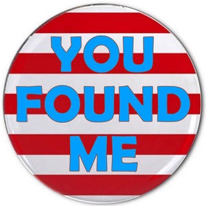 May include: A round button with a red and white striped background. The words "YOU FOUND ME" are in bold, light blue letters across the center of the button.