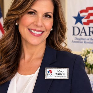May include: A rectangular name badge with a silver-toned border featuring embedded clear crystals. The white center displays the DAR logo with a blue star and red stripes, followed by the text Mary Barrow and Lady Washington Chapter.