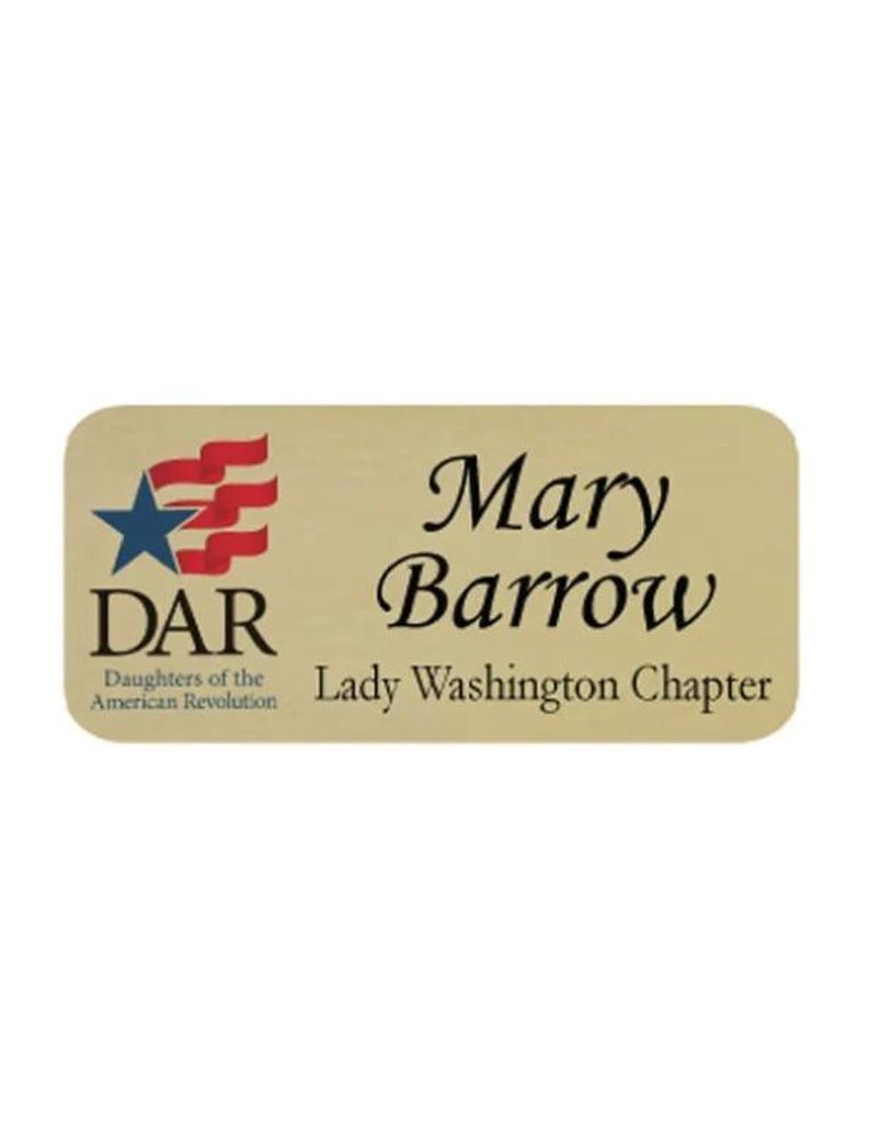 May include: A rectangular name badge with rounded corners. The badge is a light gold color and features the name "Mary Barrow" in elegant script. The DAR logo and "Lady Washington Chapter" are also displayed.