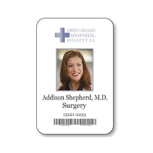 May include: A rectangular white identification badge featuring a blue cross logo and the text Grey+Sloan Memorial Hospital. It includes a portrait of a person with auburn hair, the name Addison Shepherd, M.D., Surgery, the number 13221-2254, and a barcode.