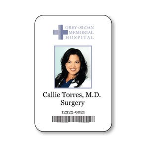 May include: A rectangular white identification badge featuring the Grey+Sloan Memorial Hospital logo, a portrait of Callie Torres, M.D., the text Surgery, the identification number 12322-9021, and a black barcode at the bottom of the card.