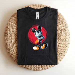May include: Black t-shirt featuring a cartoon character with a red circle background. The character is in a confident pose with arms crossed. The shirt has the word "SEAE" printed on the collar.