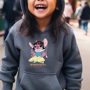 May include: A gray hooded sweatshirt featuring a cartoon character dressed as a princess. The character is pink with large ears and is holding a small blue object. The text "You make me feel like a princess" is below the character.