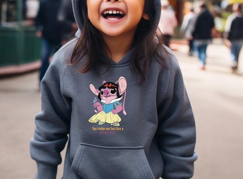 May include: A gray hooded sweatshirt featuring a cartoon character dressed as a princess. The character is pink with large ears and is holding a small blue object. The text "You make me feel like a princess" is below the character.