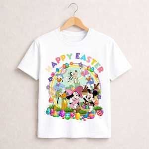 May include: White t-shirt featuring a colorful graphic of Disney characters celebrating Easter. The design includes Mickey and Minnie Mouse, Donald and Daisy Duck, Goofy, and Pluto, surrounded by Easter eggs and the words "Happy Easter."