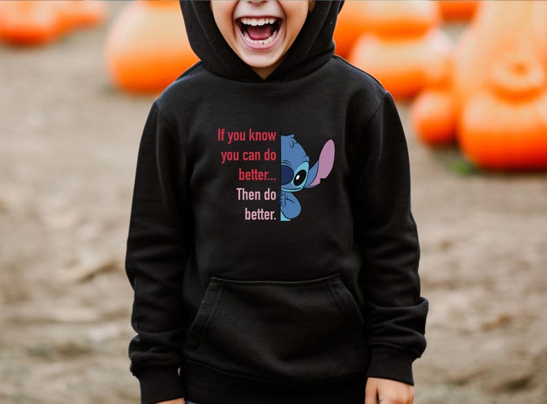 Puede incluir: Sudadera con capucha negra con un gr&aacute;fico de Stitch y el texto "If you know you can do better... Then do better." El dise&ntilde;o presenta colores azul, rosa y blanco. La sudadera tiene un bolsillo delantero y una capucha.