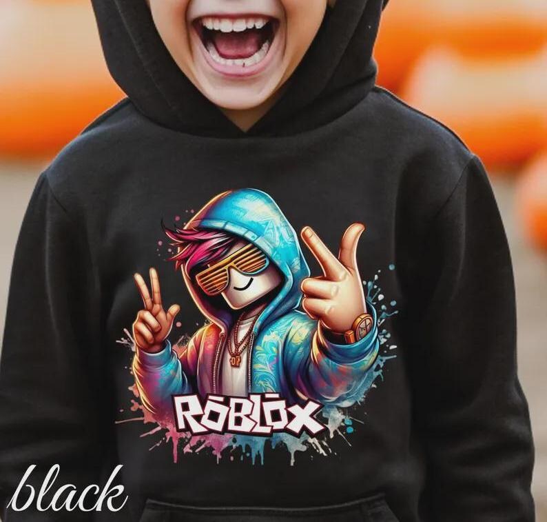Puede incluir: Sudadera con capucha negra con un gr&aacute;fico colorido de un personaje con gafas de sol y una sudadera con capucha azul, con la palabra "ROBLOX" en blanco y rosa. La palabra "black" est&aacute; escrita en cursiva en la parte inferior.