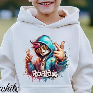 Puede incluir: Sudadera con capucha blanca con un gr&aacute;fico colorido de un personaje con gafas de sol y la palabra "ROBLOX". El gr&aacute;fico tiene una combinaci&oacute;n de colores azul, rosa y naranja. La palabra "white" est&aacute; impresa en la parte inferior izquierda.