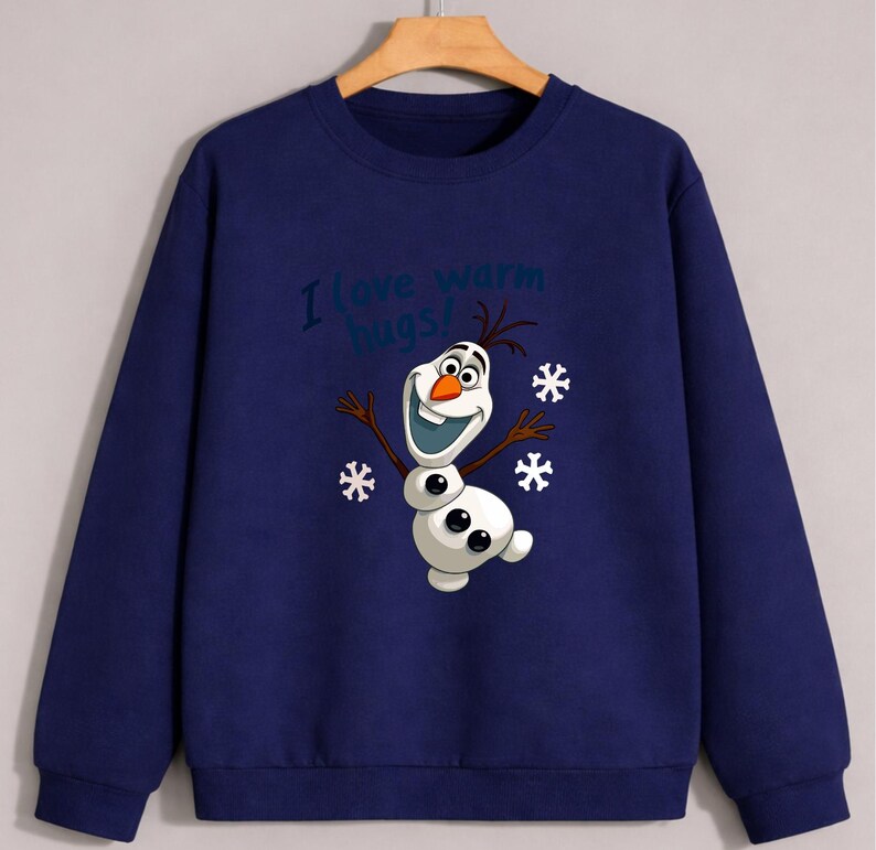 May include: Navy blue sweatshirt featuring a cartoon image of Olaf the snowman with the text "I love warm hugs!". The design includes snowflakes and Olaf's smiling face. The sweatshirt is a comfortable, casual style.