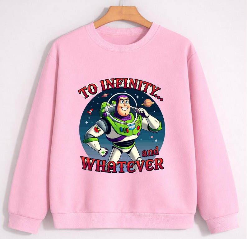 Op de afbeelding: Een lichtroze sweatshirt met een afbeelding van Buzz Lightyear uit Toy Story. De cartoonafbeelding staat tegen een sterrenachtergrond en bevat de tekst "TO INFINITY... and WHATEVER". De sweatshirt heeft een ronde hals en lange mouwen.